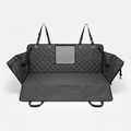 The black quilted seat cover seen from the front, spread across a rear bench with the headrest straps raised and the mesh window centred