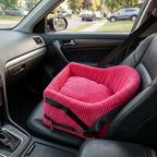 Pink pet seat cover on a car seat with a blurred street scene outside