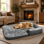 A golden retriever rests on a large gray inflatable pet bed with a built-in pillow in a cozy living room with a fireplace and sofa.