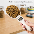 Digital pet food measuring scoop with a digital display held by a hand, surrounded by pet food containers on a wooden surface. | Pet Grooming | Pet Supplies and Food Australia | Pet Supplies Sydney | PetNexa Australia | Shop now