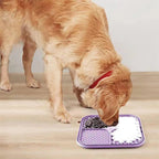 Golden retriever licking food from the purple mat